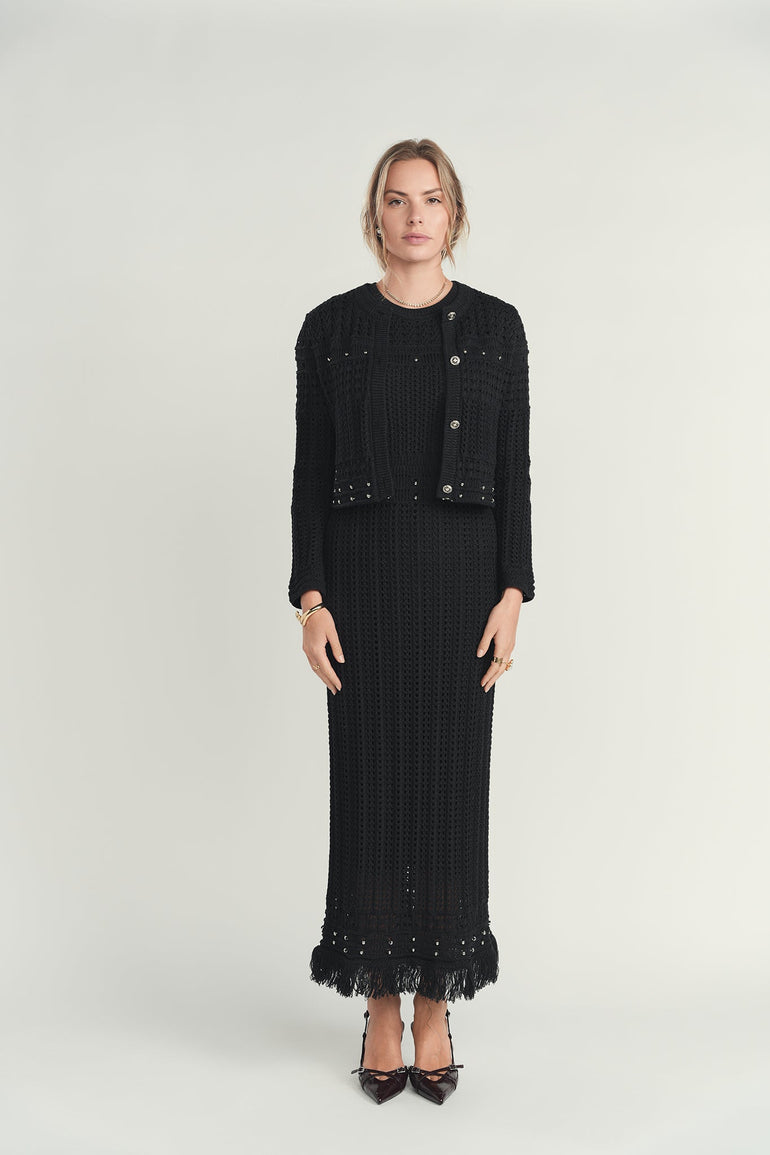 Woman wearing a black outfit with a jacket and skirt on a white background